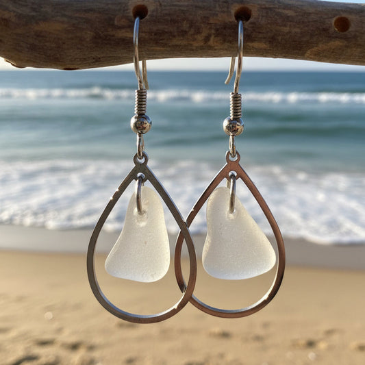 Teardrop-shaped earrings hanging on a wooden stick with a natural background.