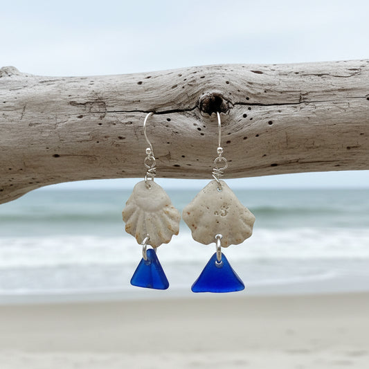 Handmade sea glass earrings on a Sea Glass & Sunsets card with a blurred outdoor background.