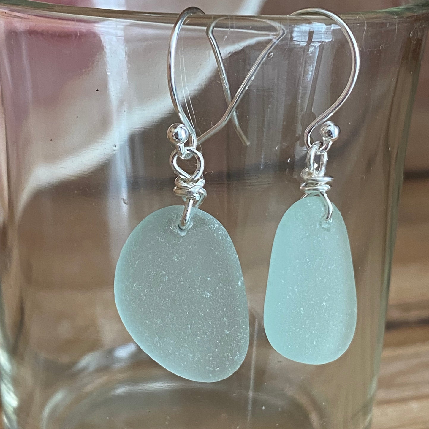 Sea Foam earrings with silver hooks displayed on a clear glass surface.